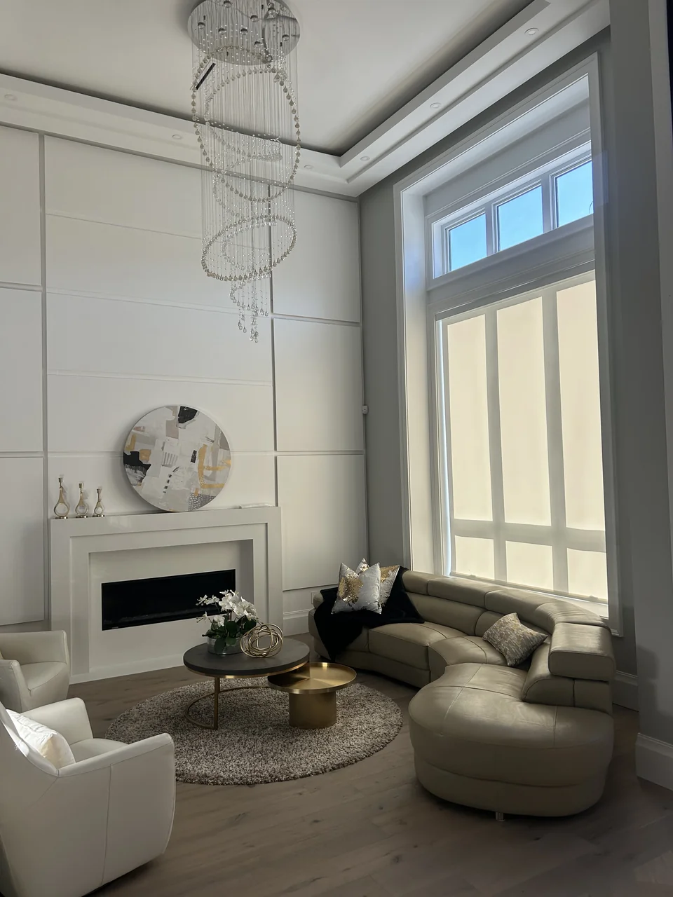 Pale roller shades behind a curved sofa with uncovered upper glazing in a Richmond living room